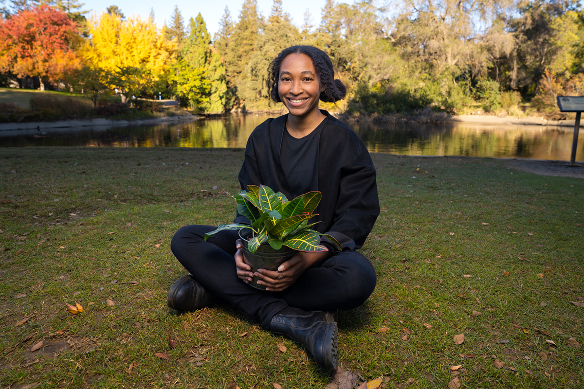 graduate student sitting outdoors with a plant